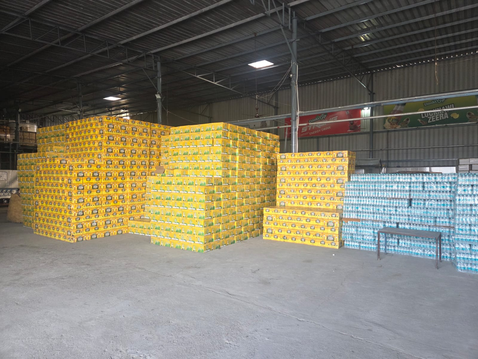 Warehouse stacked with DrinkoSip Lucknawi Zeera cases and packaged water